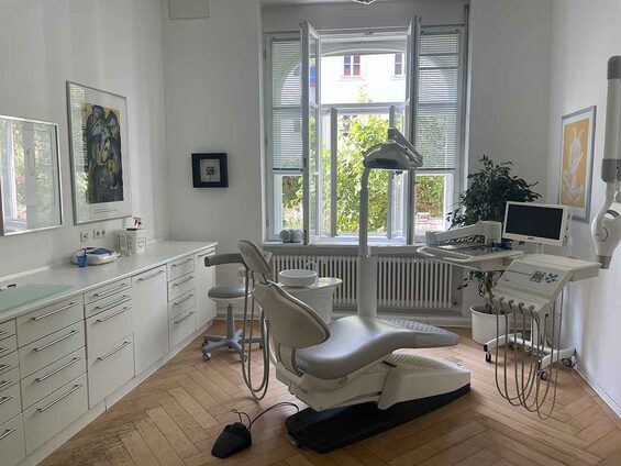 Behandlungszimmer mit Behandlungsstuhl vor großem Altbaufenster