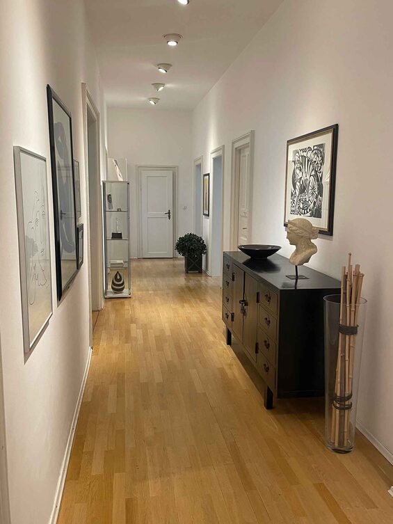 Heller Flur der Zahnarztpraxis mit Parkettboden, Kunstwerken und Sideboard